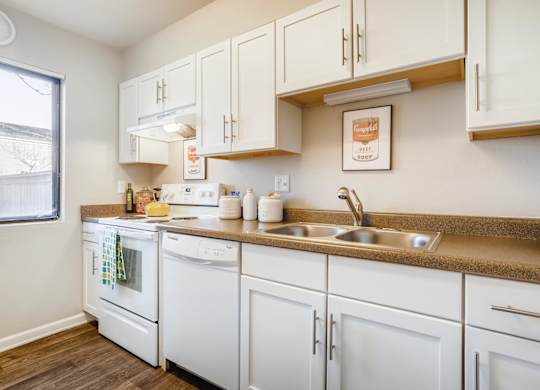 A kitchen with white appliances and cabinets at The Ranch at Bear Creek Apartments, Lakewood, CO, 80227