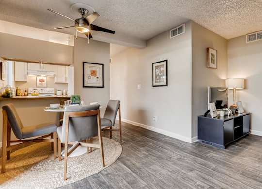 A living room with a grey chair and a wooden table at The Ranch at Bear Creek Apartments, Lakewood
