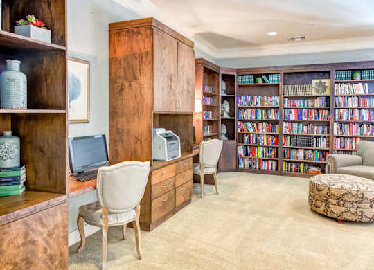 Wooden bookshelves, desks with computers, and comfortable seating areas at The Laurel at Vintage Park 55+ Apartments, Tomball Texas
