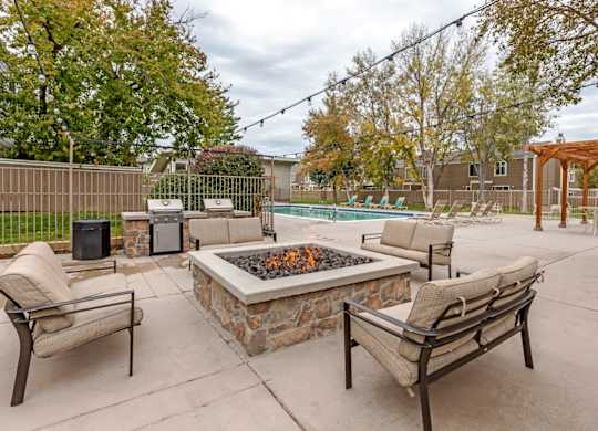 A patio with a fire pit and chairs at The Ranch at Bear Creek Apartments, Colorado
