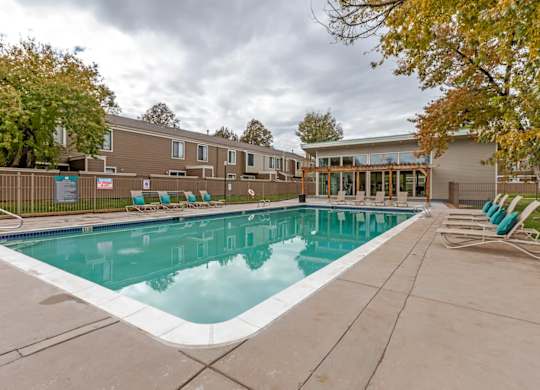 A swimming pool surrounded by a concrete floor and a wooden fence at The Ranch at Bear Creek Apartments, Lakewood