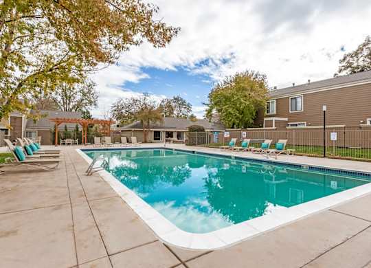 A large outdoor swimming pool surrounded by lounge chairs at The Ranch at Bear Creek Apartments, Lakewood, Colorado