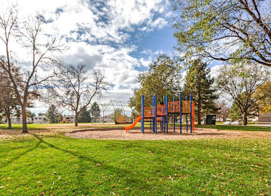 A playground with a slide and a green lawn at The Ranch at Bear Creek Apartments, Lakewood, CO