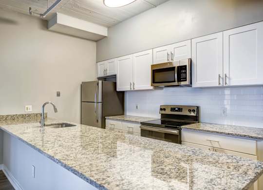 A kitchen with granite countertops and white cabinets.at 222 Saratoga, Maryland, 21202