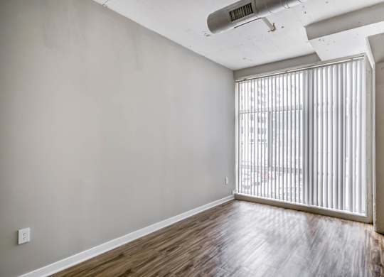 A room with wooden flooring and a window with blinds.at 222 Saratoga, Baltimore, MD