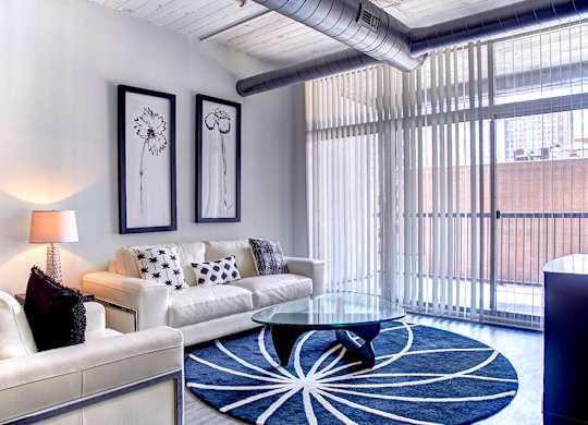 A living room with a white couch, a blue rug, and two framed pictures on the wall.