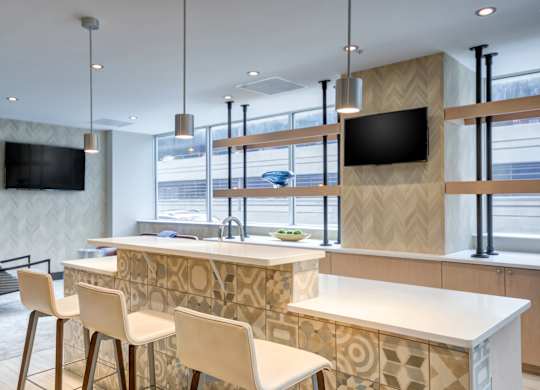 A modern kitchen with a bar area and a television mounted on the wall.