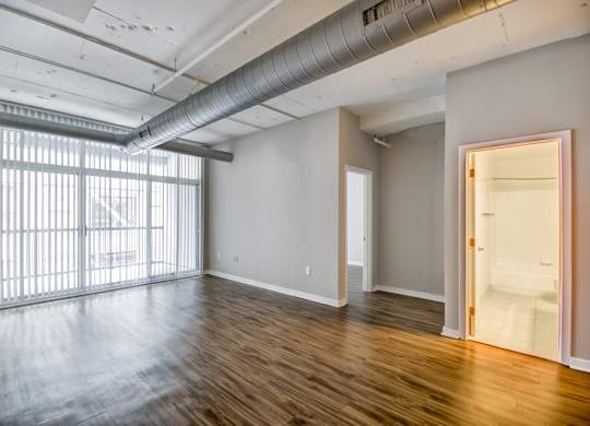 A room with wooden floors and a large window with blinds.