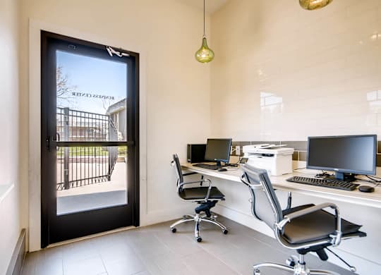 A modern office with a view of a gate and trees outside at Mountain Vista Apartments, Lakewood, CO