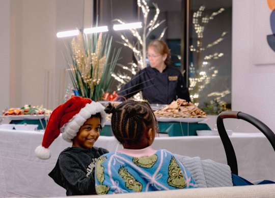 A boy wearing a Santa hat is sitting at a table with a plate of food in front of him at Metro 303, Hempstead, NY, 11550