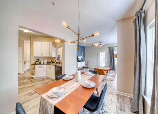 a dining area with a wooden table and chairs and a kitchen in the background at Meridian Obici, Suffolk, VA