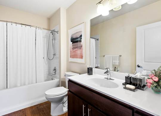 A white toilet sits next to a white bathtub in a bathroom  at Metro 303, Hempstead, NY, 11550