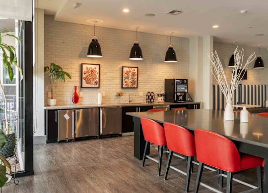 A modern kitchen with red chairs and a wooden floor at Regatta Sloans Lake Apartments, Denver, Colorado