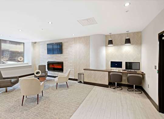 A modern living room with a fireplace and a desk with two computers.