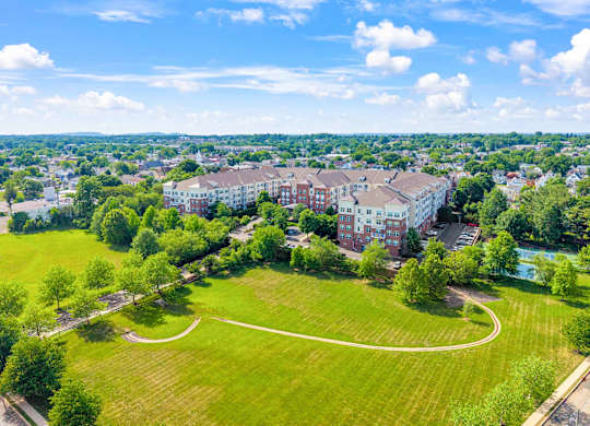 A large grassy field with a circular pathway in the middle and a building in the background.