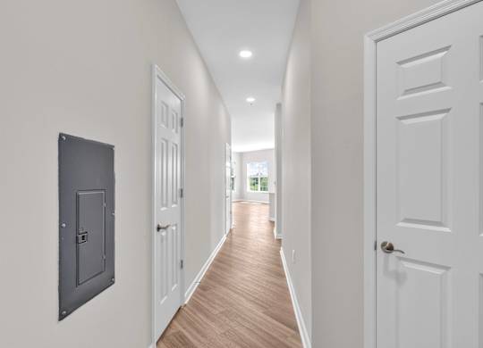 A long hallway with white doors and a black box on the wall.