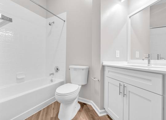 A white toilet in a bathroom with a white tub and sink.