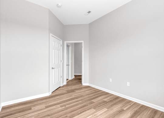A room with wooden flooring and two doors.