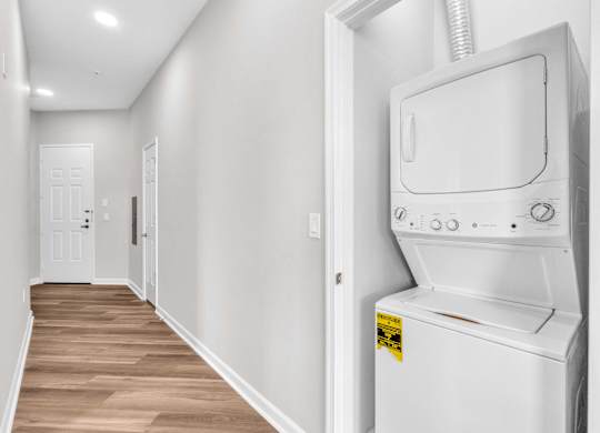 A white washing machine is in a narrow hallway.
