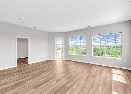 A large empty room with wooden floors and windows.