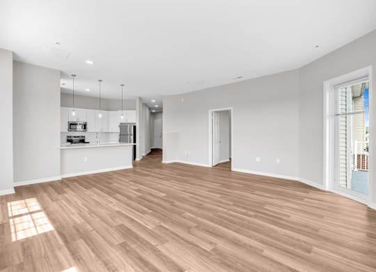 A spacious room with wooden flooring and white walls.