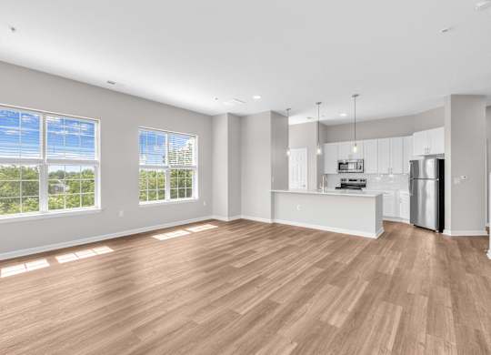 A spacious room with wooden flooring and large windows.