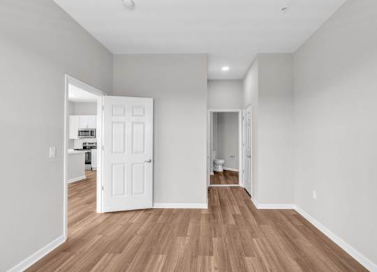 A room with a white door and wooden flooring.