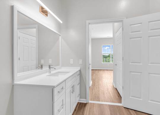 A white bathroom with a sink and mirror.