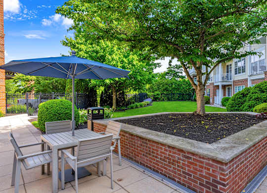 A patio with a table, chairs, and a blue umbrella.