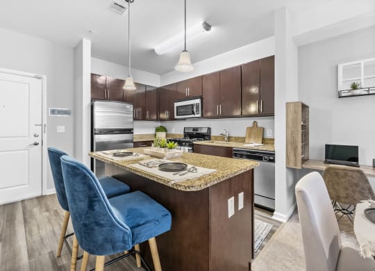 a kitchen with an island with a breakfast bar and two blue chairs  at Harbor Pointe, Bayonne, NJ