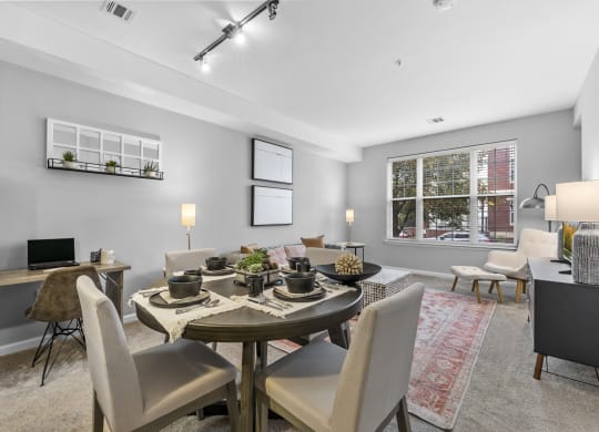 a living room with a large window and a dining room table with chairs  at Harbor Pointe, Bayonne, NJ