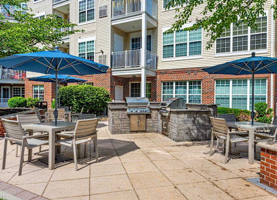A patio with chairs and umbrellas in front of a brick building.