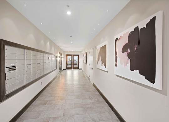 A hallway with artwork on the wall and a row of mailboxes on the left.