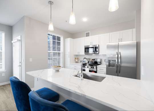 A modern kitchen with a white countertop and blue chairs.
