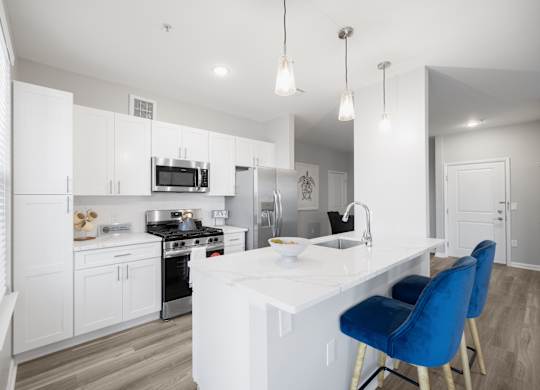 A modern kitchen with a white countertop and blue chairs.