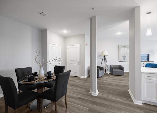 A dining room with a table set for two and a kitchen area in the background.