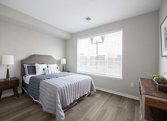 A bedroom with a bed, nightstand, and window.