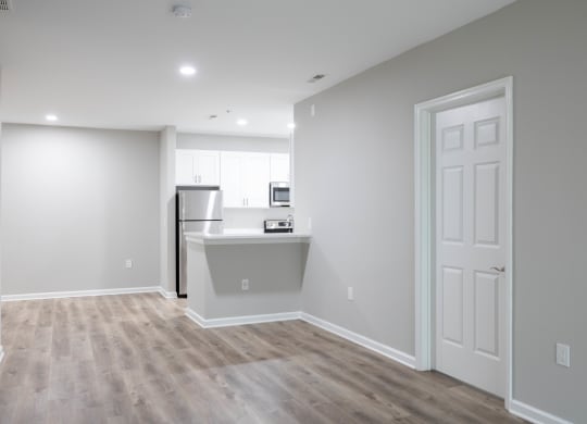 an empty living room with a kitchen in the background at The Lena, Raritan, NJ 08869