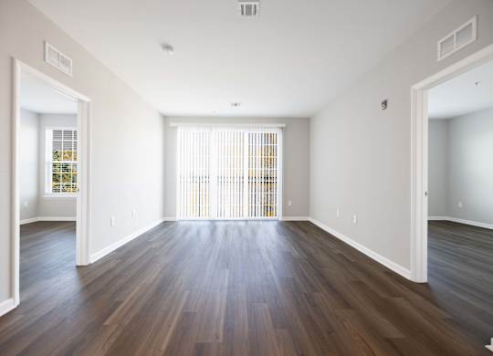 A large empty room with wooden floors and white walls.