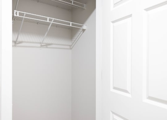 a walk in closet with a white door and a white wall with a hanging rack at The Lena, Raritan, NJ 08869