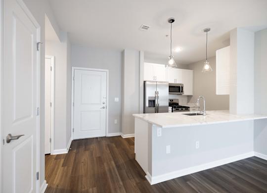 A kitchen with white cabinets and a wooden floor.