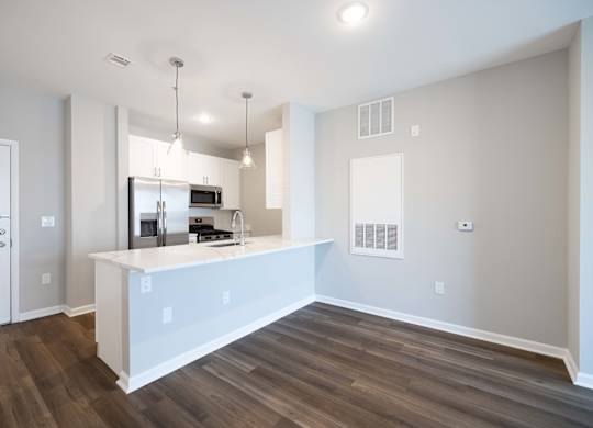 A kitchen with a white countertop and wooden flooring.