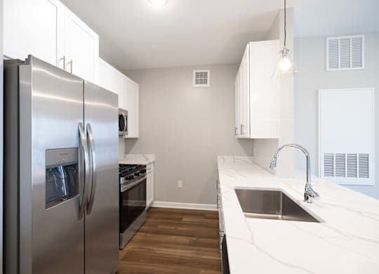 A modern kitchen with a stainless steel refrigerator and a marble countertop.