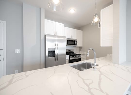 A kitchen with a marble countertop and stainless steel appliances.