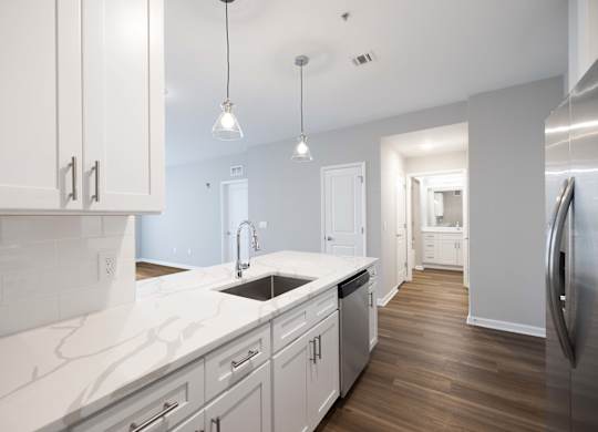 A kitchen with white cabinets and a marble countertop.