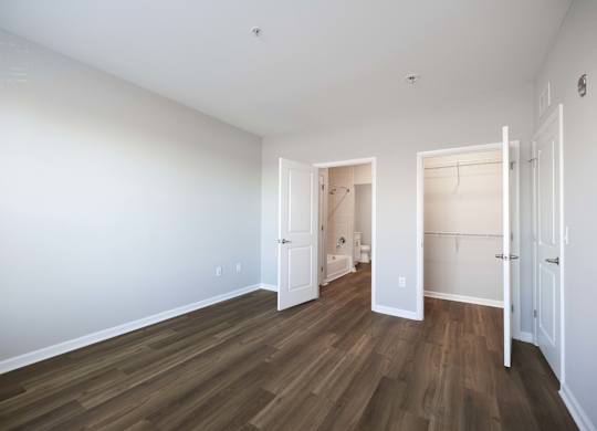A room with white walls and wood flooring, with two open doors.