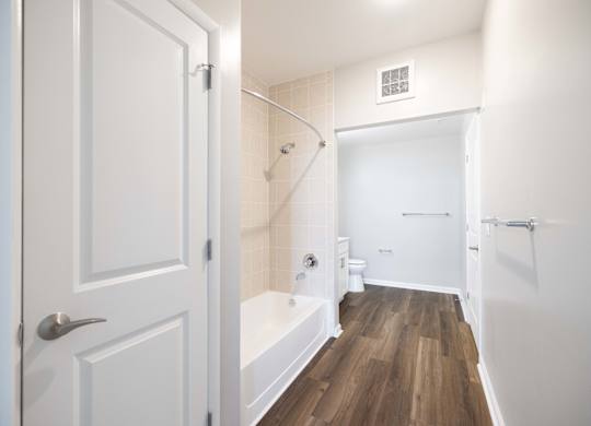 A white bathroom with a wooden floor and white walls.