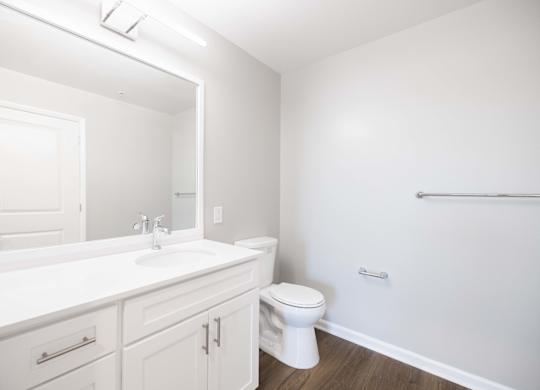 A white bathroom with a toilet, sink, and mirror.