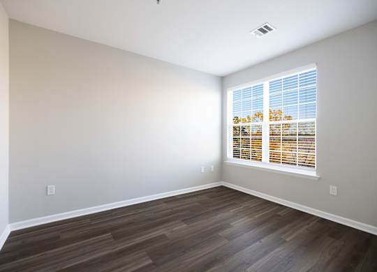 A room with wooden flooring and a window with blinds.