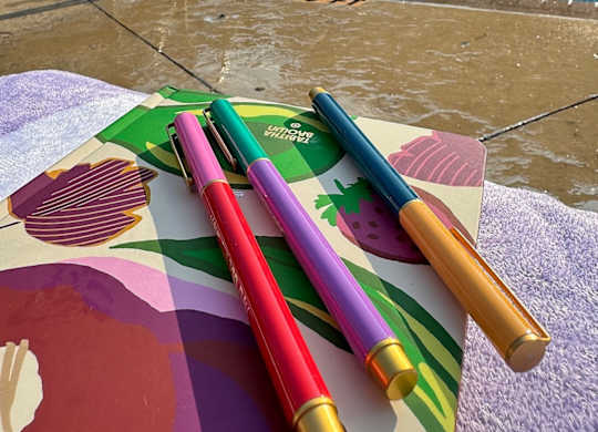 A pool with a waterfall and a table with four pens on it.